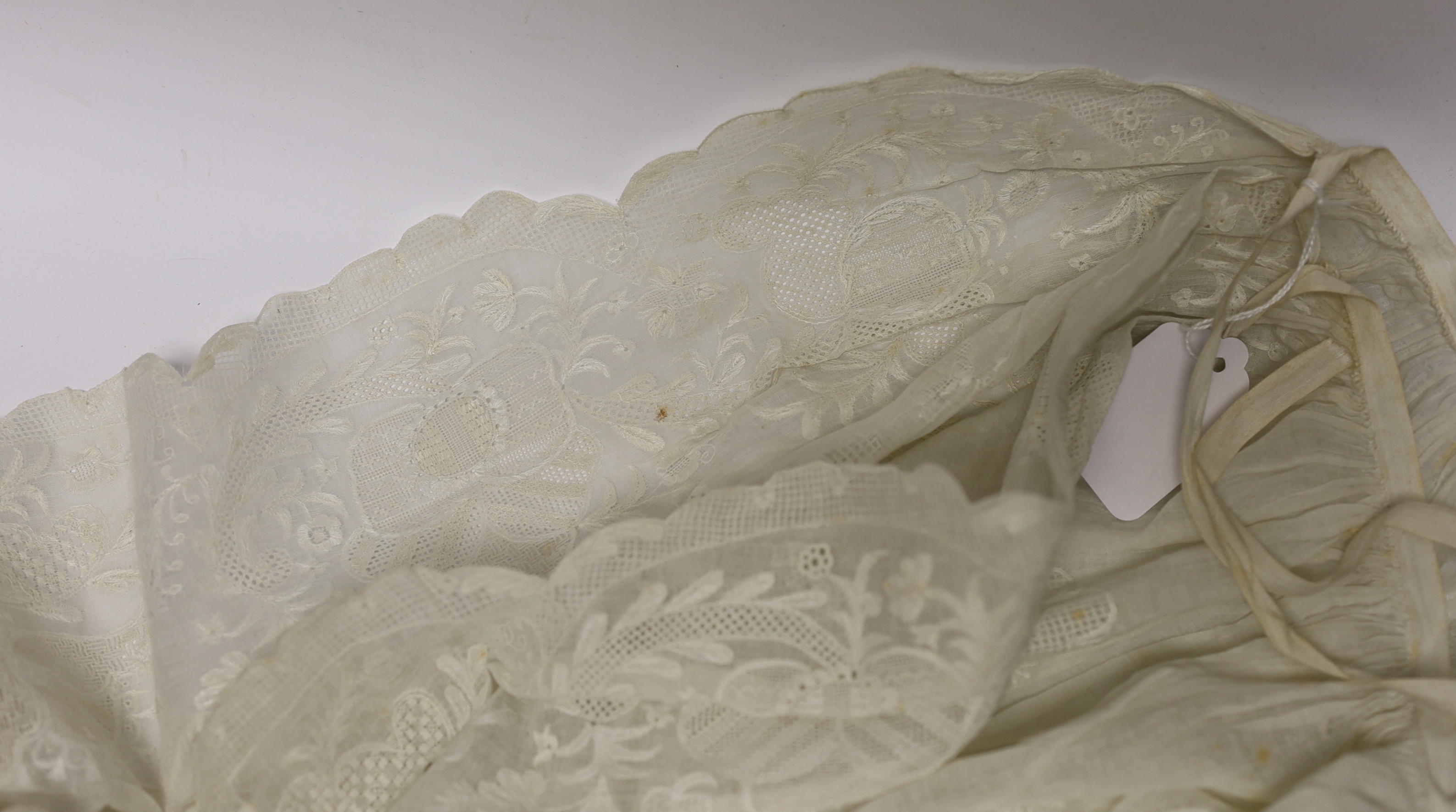 An 18th century Dresden worked apron, a white worked fine lawn stole, two panels of linen ribbon work, a ladies lace bonnet a similar pink satin bonnet a white worked blouse (partially made) and panel to a christening go